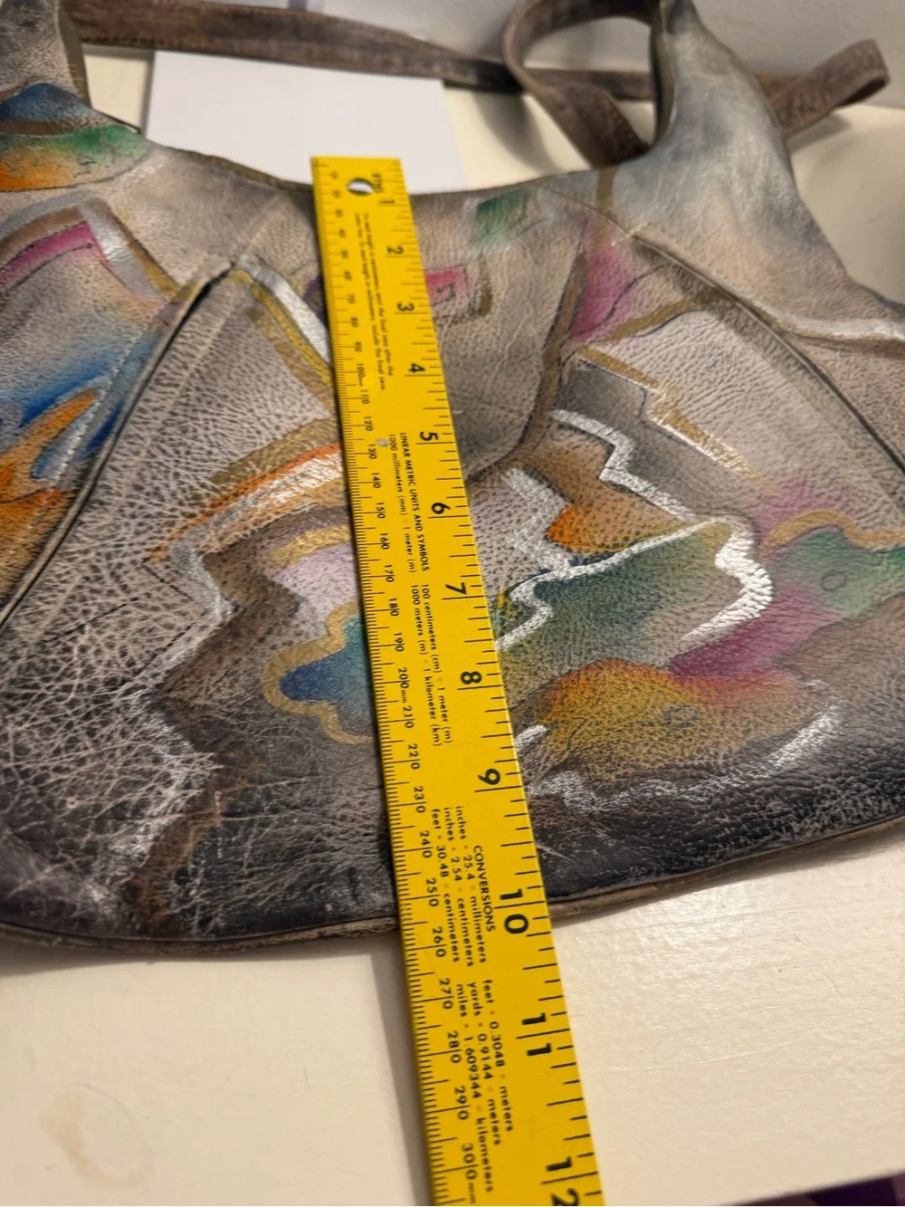 Distressed leather hobo bag with colorful abstract design on front and back.